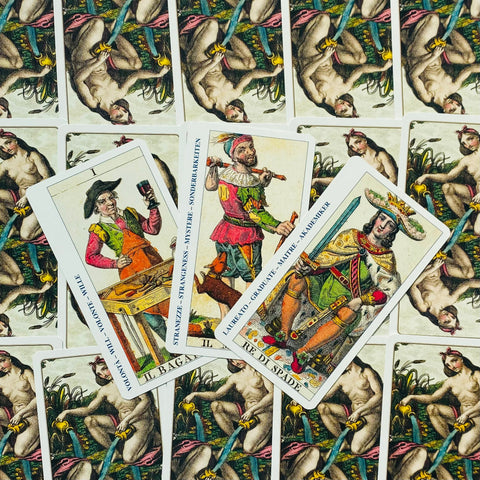 tarot kortos su trimis išdėstytomis didžiosiomis kortomis centre, spalvingi istoriniai personažai ir kortelių nugarėlė fone