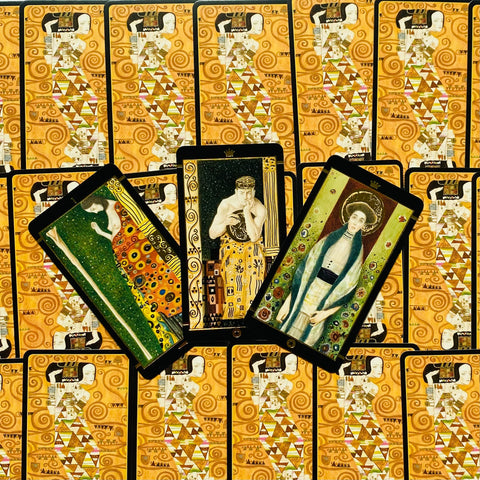 Tarot kortos Klimto stiliaus komplektas, trys skirtingos priekinių kortų iliustracijos fanuotos virš auksinių nugarėlių rašto, detalė parduotuvės galerijai