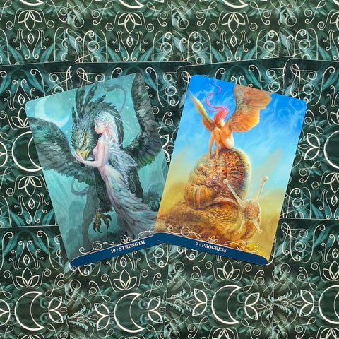 tarot kortos atviros: Strength ir Progress su fantaziškais piešiniais, padėtos ant žalių nugarėlių