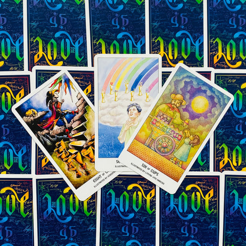 Tarot kortos trijų kortų išdėstymas su spalvingomis iliustracijomis, mėlynu graviruotu fonu ir baltais kraštais