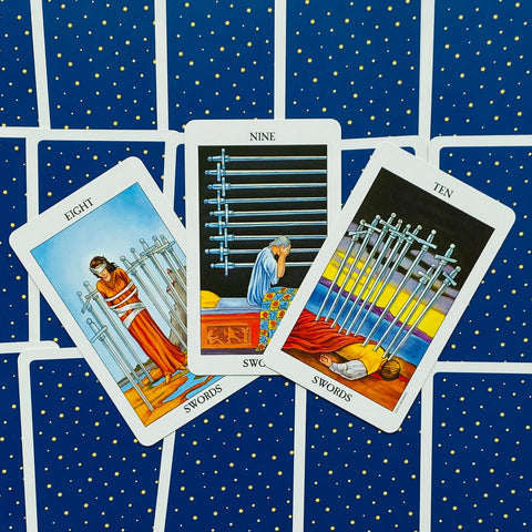 Tarot kortos – mėlynos nugarėlės komplektas su išskleista trijų kalavijų seka (Aštuoni, Devyni, Dešimt) centre