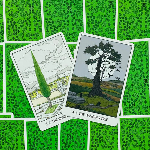 tarot kortos, dvi atverstos kortos (The Cemetery ir The Hanging Tree) iš arti, matyti priekinės iliustracijos ir ryški žalia nugarėlė