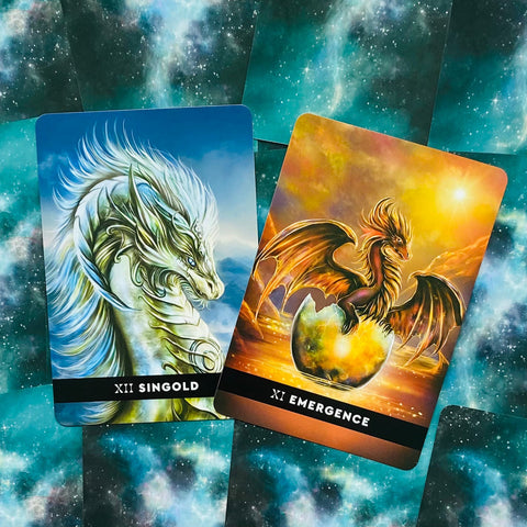 Tarot kortos — dvi atverstos kortos: mėlyna Singold drakono korta ir auksinė Emergence kiaušinyje gimstanti drakono korta, skiriasi spalva ir motyvu