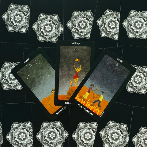 tarot kortos juodu kraštu, trijų lazdelžių kortų išdėstymas centre: pergale, drąsa ir konfliktas ant ornamentuoto fono