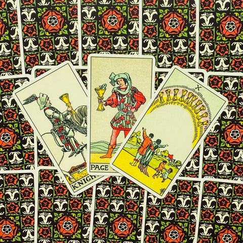 Tarot kortos – trys taurės fanuotos centre ant raštuotos raudonai–juodos nugarėlės, ryškios spalvos ir detalės