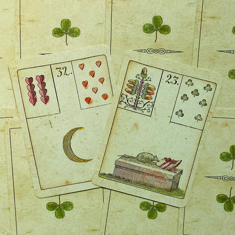 Kortos Lenormand stiliaus, sendintos kreminės, dvi atvertos kortos (Mėnulis ir Karstas) ant nugarėlių su dobilų raštu