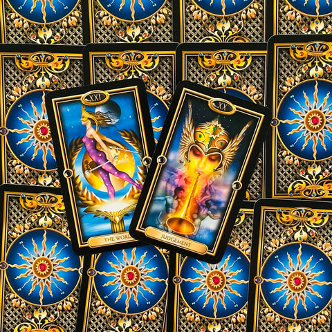 Tarot kortos atverstos centre su Pasaulis ir Teismas major arcana kortomis, aukso rėmai ir mėlynos nugarėlės raštas