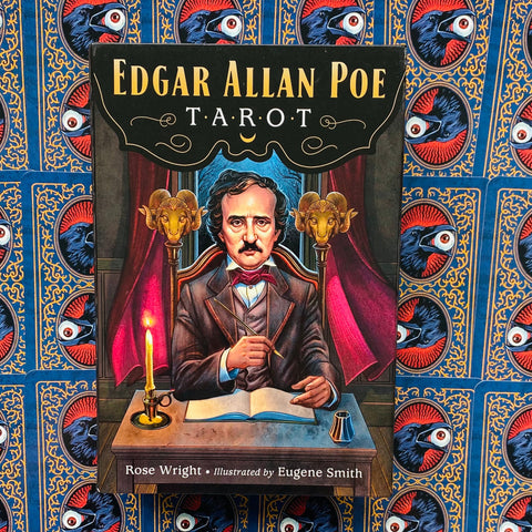 Edgaro Allano Poe taro kortų dėžutė su Poe portretu, auksinėmis detalėmis ir žvake ant mėlyno raštuoto fono