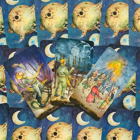 Tarot kortos su mėlynais mėnulio nugarėliais, trys priekinių kortų variantai (8, 9 ir 10 lazdų) demonstruoja detalų, rankų pieštą meną