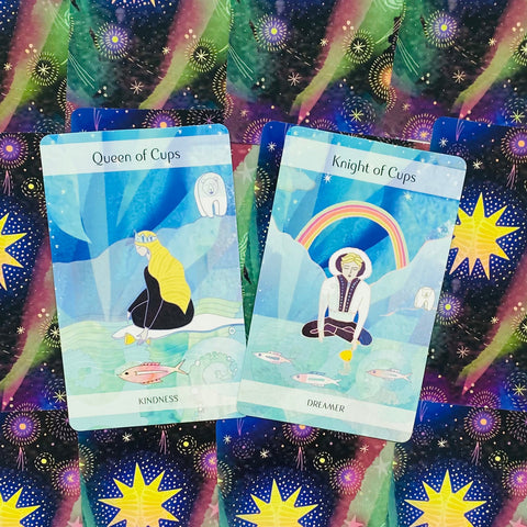 Tarot kortos su mėlynomis iliustracijomis, rodantis Queen of Cups ir Knight of Cups priekyje ant žvaigždėto fono