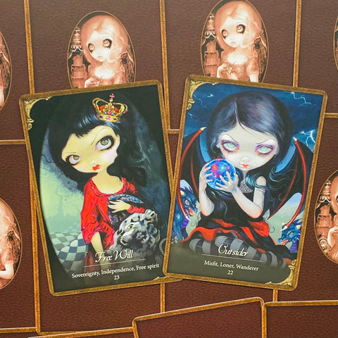 Tarot kortos su dviem gotikinėmis iliustracijomis – Free Will raudona ir Outsider mėlyna versijos ant rudo fono