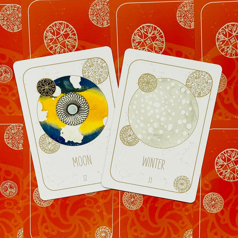 Tarot kortos rinkinyje dvi iliustruotos kortos „Moon“ ir „Winter“ ant raudono ornamentuoto fono, skirtos variantų demonstravimui