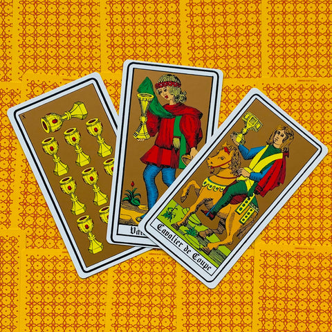 tarot kortos Marseille stiliaus, trys taurės priekinės kortos su spalvotu piešiniu ant raštuoto geltono fono