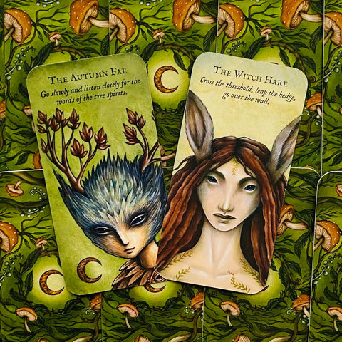 Orakulo kortos su žaliu grybų raštu: dvi atverstos kortos — The Autumn Fae ir The Witch Hare, detalios iliustracijos frontuose