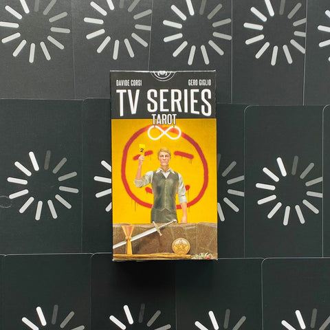 TV Series Tarot dėžutės priekinis vaizdas: geltona pakuotė su figūra laikančia kortą, centroje ant juodo raštuoto fono