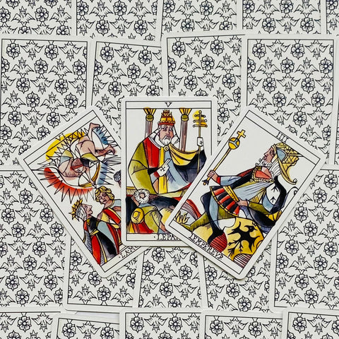 Taro kortos trijų atverčių variantas su spalvingais Major Arcana vaizdais ant gėlėmis dekoruotų nugarėlių, fotografuota iš viršaus