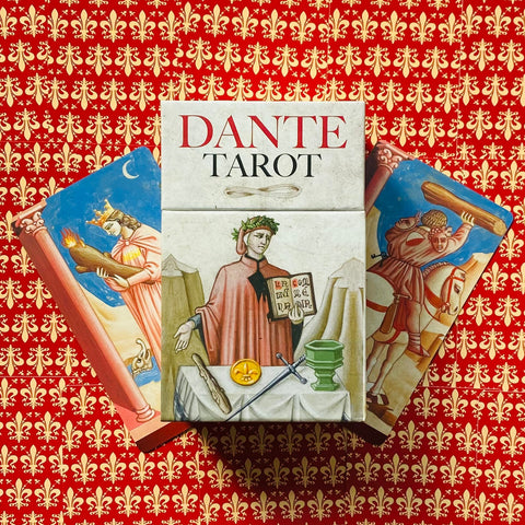 Dante tarot kortos: dėžutė su Dante iliustracija ir dvi išskleistos kortos ant raudono ornamentuoto fono