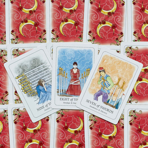 Tarot kortos su raudonomis nugarėlėmis: trys atverstos Kardų serijos kortos (Nine, Eight, Seven), centre užrišta Eight of Swords, išdėstytos vėduoklės formoje