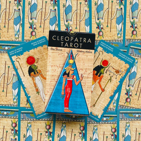 Cleopatra Tarot kortų rinkinys su mėlyna dėže ir raudonai apsirengusios Egipto figūros priekyje, išdėstytas ant atverstų kortų fono