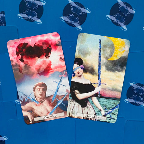 Tarot kortos – dvi iliustruotos Kalavijų kortos (3 ir 9) ant mėlyno fono, horizontaliai išdėstytos, artimas kampas