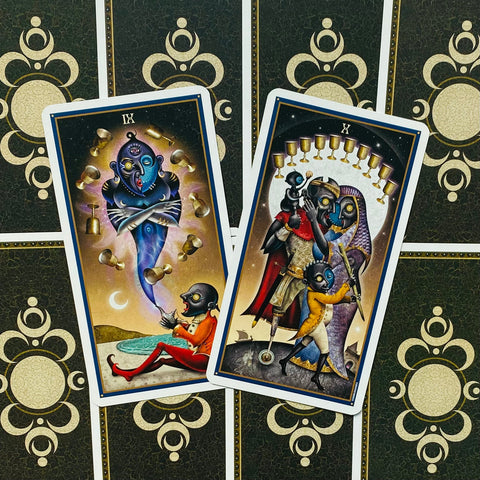 tarot kortos dvisienės iliustracijos (IX ir X), ryškūs mėlyno ir aukso tonai, padėtos ant tamsiai žalios galinės pusės