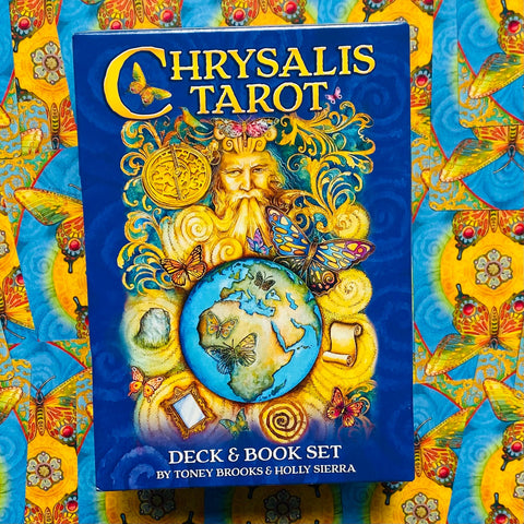 Chrysalis tarot kortų ir knygos rinkinys su ryškiai mėlynu viršeliu, spalvotomis drugelių iliustracijomis ir raštuotu geltonu fonu