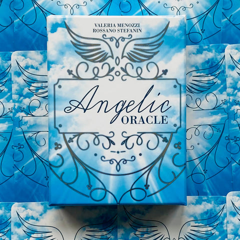 Angelic Oracle kortos mėlyname debesuotame dėkle su stilizuotais angelo sparnais ir ornamentiniais raštais, užfiksuotos iš viršaus