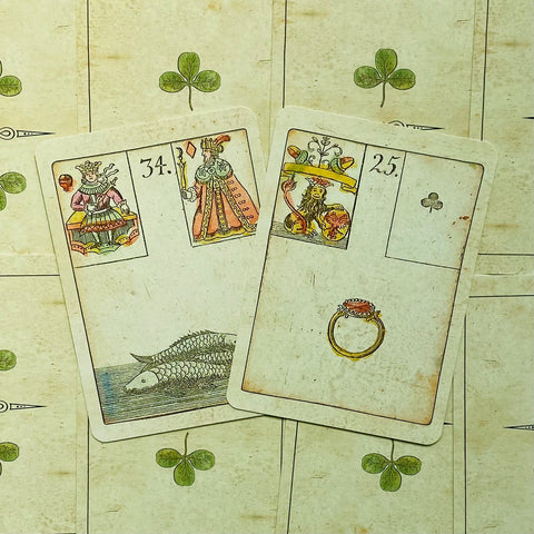 Kortos vintage lenormand rinkinys su rankų pieštomis žuvis ir žiedo kortomis ant žalio dobilų fono, kampu išdėstytos