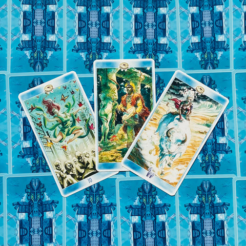 Tarot kortos su atvertais priekiais: trys iliustruotos kortos (centre šamanas, kairėje skraidanti figūra, dešinėje raitelis ant buliuko) ant mėlyno nugarėlių fono