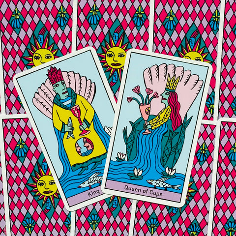 Tarot kortos su dviem atvertomis King of Cups ir Queen of Cups kortomis, ryškūs rožiniai bei mėlyni piešiniai ant ornamentuoto fono