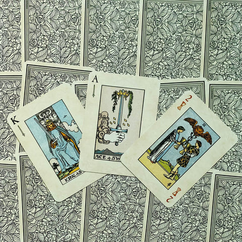 tarot kortos su klasikiniais paveikslais – Ace of Swords, King of Swords ir Two of Cups atverstos ant ornamentuoto nugarėlių fono
