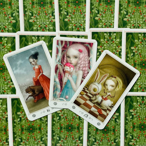 Tarot kortos su trijų atvertų kortų meninėmis iliustracijomis ir žaliu augalinio rašto nugarėle, arti fotografuota