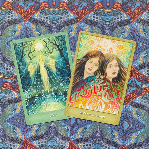 Orakulo kortos atverstos dviem kortomis: žydrai žalia „Nyx“ su mėnulio moterimi ir šiltų tonų „Mystic Sisters“ korta