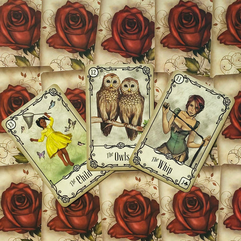 Tarot kortos su raudonų rožių nugara, trys atidengtos kortos (Vaikas, Pelėdos, Vytis) demonstruoja pakuotės dizainą.