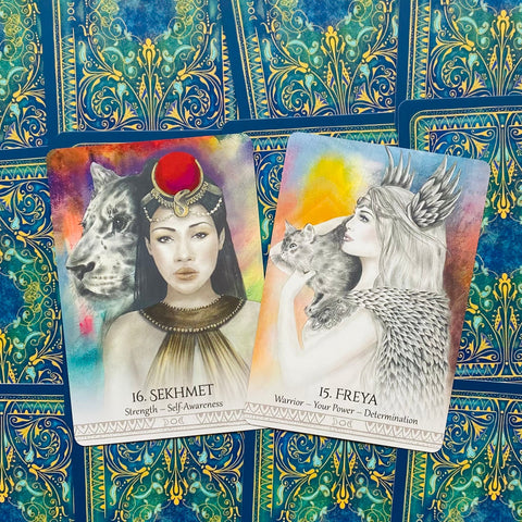 orakulo kortos atverstos: Sekhmet ir Freya kortos su spalvotais piešiniais ant mėlyno ornamentuoto fono