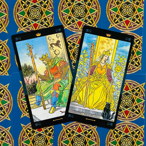 Tarot kortos – dvi atverstos Lazdų kortos (karalius ir karalienė) geltonais ir žaliais tonais ant mėlyno ornamentuoto fono