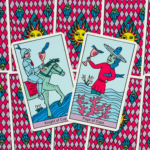 Tarot kortos su ryškiai rožine rombų nugara ir dviem atverstomis mėlynomis kortomis (Knight ir Page of Cups) centriniame kadre