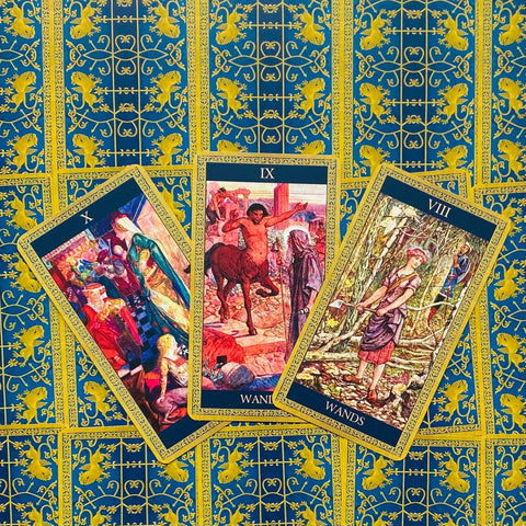 Tarot kortos trijų kortų išklotinė: auksinis-mėlynas galas ir trys atverstos Lazdų kortos (VIII, IX, X)