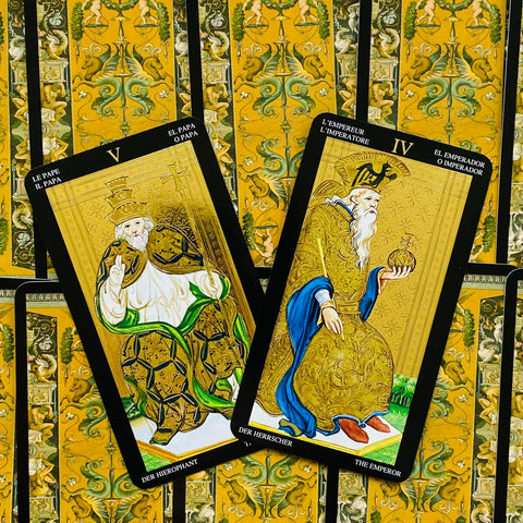 tarot kortos – prabangus rinkinys su auksinėmis geltonomis nugarėlėmis ir atverstomis Imperatoriaus (IV) bei Hierofanto (V) kortomis