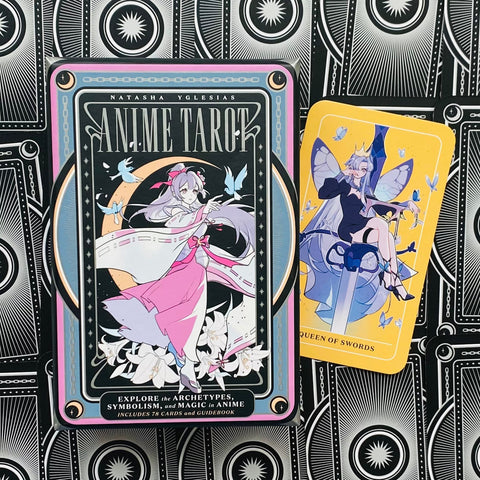 Anime tarot kortų rinkinys – juodos dėžutės priekinis dizainas su rožine anime figūra ir geltoną „Queen of Swords“ kortą, parodo dėžutės bei kortų dizainą pirkėjams