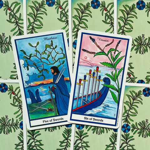 Tarot kortos Rider‑Waite stiliaus, dvi atvertos kortos — Penki kalavijai ir Šeši kalavijai persidengiant ant žalio augalinio rašto fono