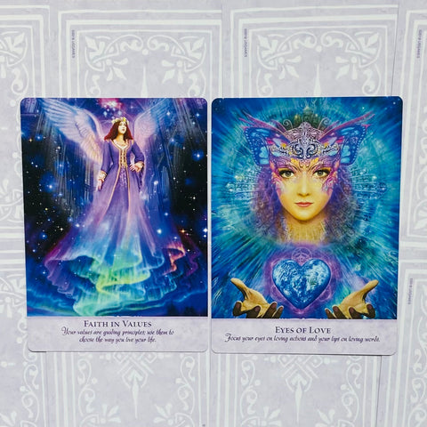 Orakulų kortos – dviejų kortų komplektas, kairėje violetinė „Faith in Values“ angelas, dešinėje mėlyna „Eyes of Love“ su širdimi