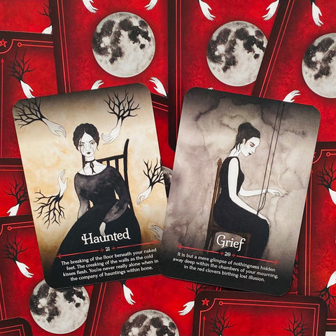 tarot kortos, dvi iliustruotos kortos Haunted ir Grief ant raudonos mėnulio nugarėlės fono
