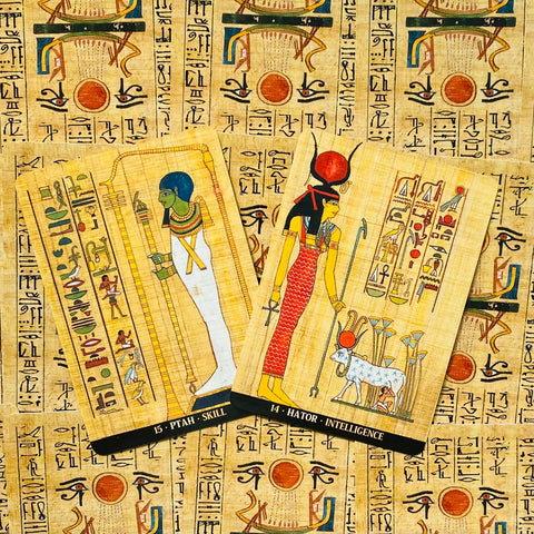 Tarot kortos rinkinys su Egipto dievų motyvais, dvi išklotos kortos (Ptah ir Hator) ant papiruso fono