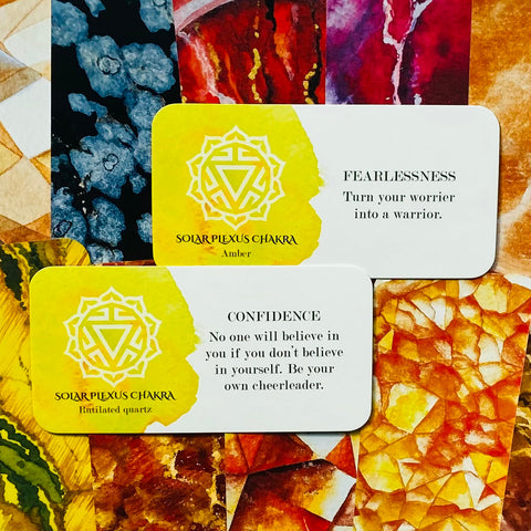 Chakros kortelės saulės rezginiui, geltoni variantai su skirtingomis akmeninėmis etikėtėmis — viena „Fearlessness“ (Amber), kita „Confidence“ (Rutilated quartz)