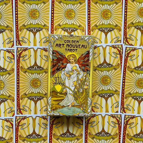 Produktų puslapyje matoma priekinė Golden Art Nouveau Tarot dėžutė auksinės–geltonos kortų nugarėlės fone, centre, parodyta produkto variantui