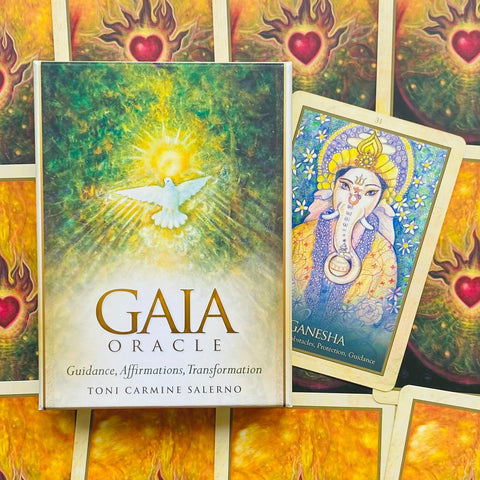 Gaia Oracle kortos dėžutė su baltu balandžiu ir šviesos motyvu, šalia atversta Ganesha korta ryškiame fone