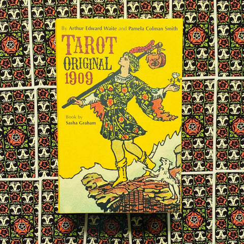 tarot knyga "Original 1909" geltonu viršeliu, matomas priekinis viršelis ant dekoratyvių kortų fono