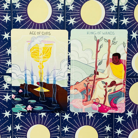 Tarot kortos su spalvingomis iliustracijomis — Ace of Cups ir King of Wands rodoma šalia ant mėlyno žvaigždėto fono