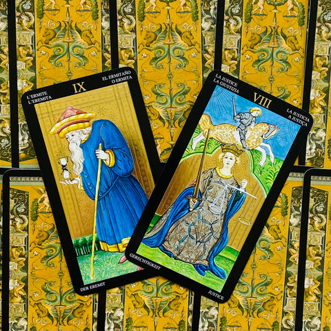Tarot kortos su mėlynomis Hermito (IX) ir Teisingumo (VIII) figūromis ant aukso raštuotos nugarėlės, pristatomos kaip pora